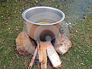 Cooking tasty delicious indian food item during a picnic or outdoor camp using stone made firewood oven and aluminium pot at an op