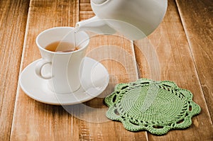 Cooking of tea in a white cup with a teapot/cooking of tea in a white cup with a teapot on a wooden background. selective focus