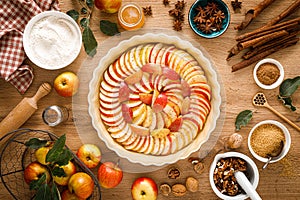Cooking Thanksgiving autumn apple pie with fresh fruits and walnuts on wooden table
