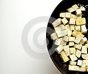 Cooking tofu in a pan on a white background