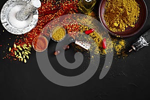 Cooking using fresh ground spices with mortar and small bowls of spice on a black table with powder spillage on its