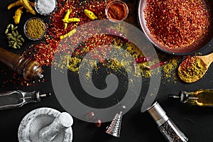 Cooking using fresh ground spices with mortar and small bowls of spice on a black table with powder spillage on its