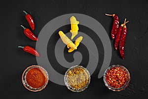 Cooking using fresh ground spices with three small bowls of spice on a black table overhead view with copyspace