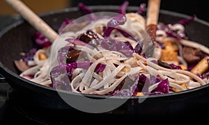 Cooking a vegan Asian Pad Thai stir fry with red cabbage, tofu and noodles.