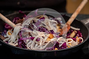 Cooking a vegan Asian Pad Thai stir fry with red cabbage, tofu and noodles.