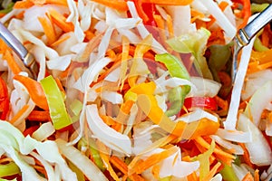 Cooking vegetarian salad with fresh raw vegetables white cabbage, carrots, red and green bell peppers healthy food Concept.