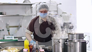 Cooking. woman chef, in protective gloves and a mask, prepares food in the kitchen, in canteen. health food and safety