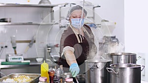 Cooking. woman chef, in protective gloves and a mask, prepares food in the kitchen, in canteen. health food and safety