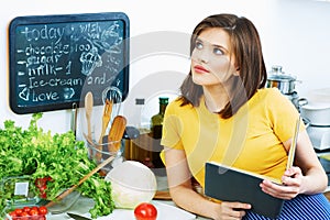 Cooking woman standing in kitchen, reed recipe from menu