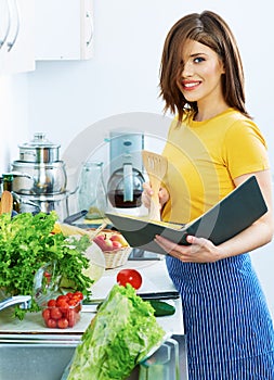 Cooking woman standing in kitchen, reed recipe from menu