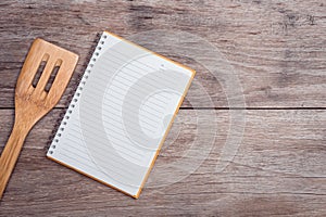 Cooking wooden spatula and lined paper on wooden table top view