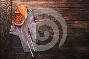 Cooking wooden utensils, basil leaves and spices on old wooden background. Abstract food background. Top view of dark rustic kitch