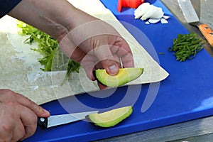 cooks hand hold knife cut avocado cooking guacamole sauce with dill, onion, tomato