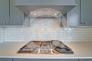 Cooktop with burners fixed on the kitchen countertop of home with exhaust hood