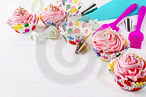 Cookware and cupcakes with pink whipped cream swirl, copy space