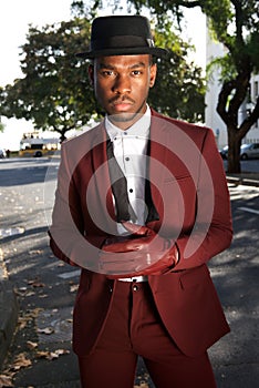 Cool african american male fashion model posing on city street with vintage suit and gloves