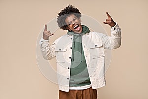 Cool African American teen guy showing rock n roll hand sign isolated on beige.