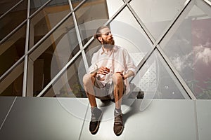 Cool bearded tattooed guy posing in front of office building