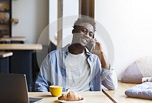 Cool black guy making phone call while sitting in cafe