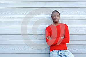 Cool black guy standing against wall with arms crossed