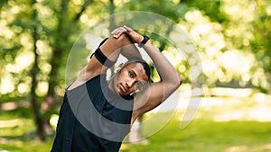 Cool black guy stretching his arm after workout at park, free space