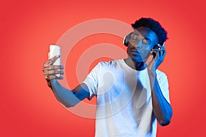 Cool black guy using wireless headset and taking selfie