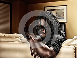 Cool black man with dreads on leather couch.