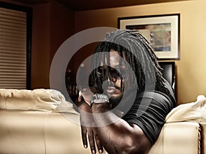 Cool black man with dreads on leather couch. photo
