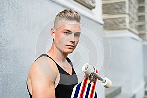 Teenage boy with scateboard in front of old building.