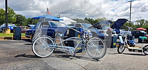 Cool blue low rider bike with spoke wheel sitting in front of old school car
