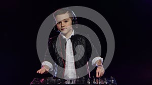 Cool boy dj in headphones playing on vinyl. Black background