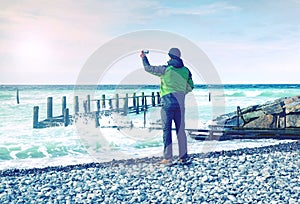 Cool boy makes photo of calm sea. Man takes picture