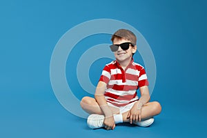 Cool boy in red striped shirt and trendy sunglasses feels happy and looking away at free empty space