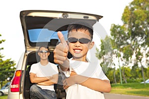 Cool boy thumb up and father across arms with car