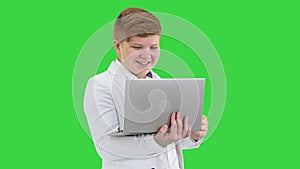 Cool Boy In White Suit Standing Using Laptop And Making Win Gesture on a Green Screen, Chroma Key.