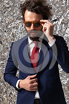 Cool businessman adjusting his sunglasses and jacket