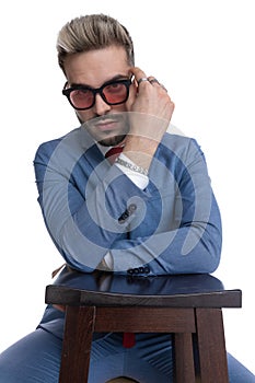 Cool businessman fixing his sunglasses, resting his arms