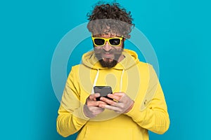 Cool casual man with long beard and moustache holding phone and texting