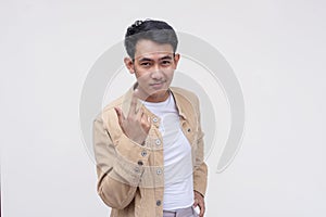 A cool and cocky asian man dares someone to approach him. Gesturing with his finger to come closer. Isolated on a white background