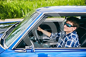 Cool confident man in sunglasses driving car