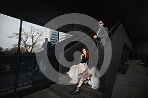 Cool couple posing on stairs near black background