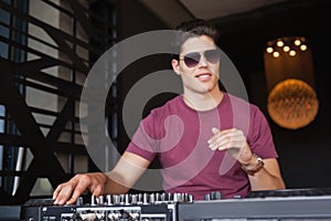 Cool dj in sunglasses working on a sound mixing desk