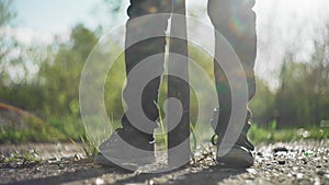 A cool dude with a baseball bat is walking on the overgrown asphalt. Close - up from the ground. Beautiful sun rays