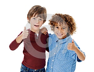 Cool dudes. Studio shot of two cute little boys giving you thumbs up against a white background.