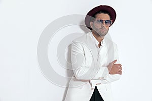 cool elegant man with hat and glasses crossing arms and posing
