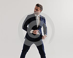 cool elegant man looking to side and arranging navy blue suit