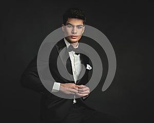 cool elegant young man buttoning his tuxedo coat