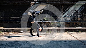 A cool, energetic Asian male hiphop dancer is practicing his b-boy breakdance on the street