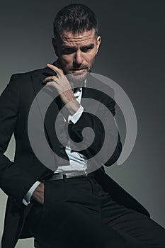 Cool fashion businessman in elegant tuxedo posing with hand in pocket
