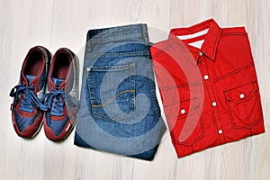 Cool fashion men`s casual outfit on wooden background, blue jeans pants, sneaker, top view